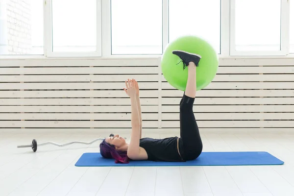 Joven chica delgada hace ejercicio y estiramiento en un fitball verde En el gimnasio brillante. Concepto de espalda y ligamento saludable . — Foto de Stock