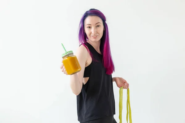 Ritratto di una giovane ragazza mista positiva e hipster con capelli colorati che tiene frullato di proteine della frutta su uno sfondo bianco con spazio per copiare. Stile di vita sano concetto — Foto Stock