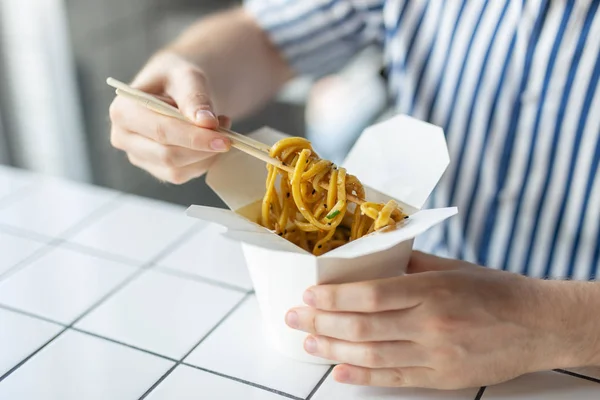 Blízcí mladí neidentifikovaný maníci v košili drží dřevěné tyčinky čínské nudle. Vynikající pojetí asijských kuchyní. — Stock fotografie