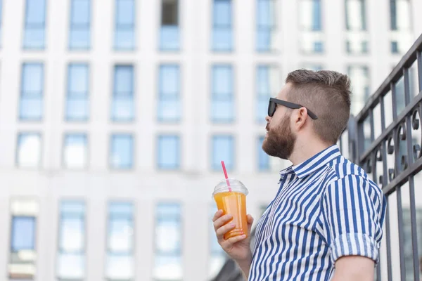 Retrato de vista inferior de un hombre hipster joven con estilo en vasos de espejo con jugo en el fondo del centro de negocios. Vacaciones urbanas en el concepto de fin de semana . — Foto de Stock