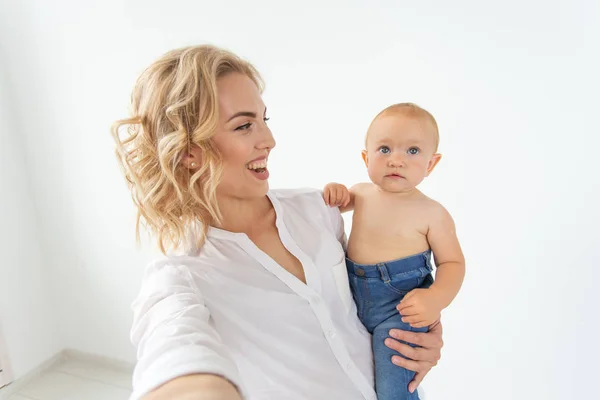 Rodzina i macierzyństwo koncepcja-szczęśliwy młody blond matka z małym dzieckiem biorąc selfie — Zdjęcie stockowe