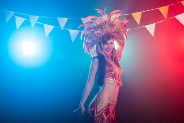 Kabare, dansçı ve tatil konsepti - Koyu arka plan üzerinde parlak renkli karnaval kostümsevimli genç kız