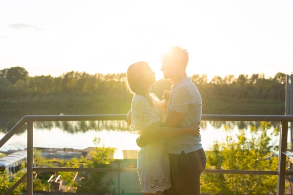 Uomo e donna che si abbracciano al tramonto sulla natura. Coppia in romantico abbraccio — Foto Stock