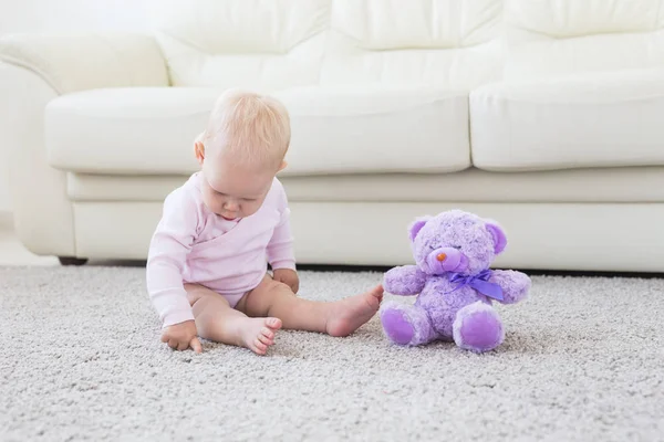 Cute little baby girl noszenia różowe ubrania siedzi na dywanie — Zdjęcie stockowe