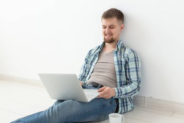 Rahat giysiler ve gözlük Internet Wi-Fi ve Kiralık Konut arayışı içinde bir dizüstü bilgisayar kullanarak sörf olumlu genç adam. Ev ve daire arama konsepti.