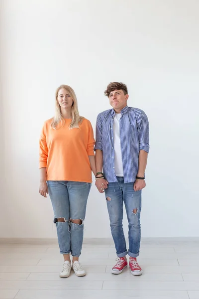 Porträtt av en glad ung positiv par i full tillväxt klädd i casual kläder poserar på en vit bakgrund. Konceptet med snygga unga moderna människor. — Stockfoto