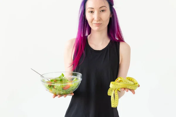 Молодая блоггерша фитнес держит овощной салат и измерительную ленту. Концепция спортивного образа жизни и правильного питания . — стоковое фото