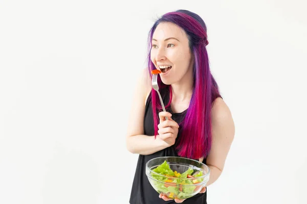 Chica hipster mestiza positiva con el pelo coloreado comiendo una ensalada griega ligera después del entrenamiento físico. El concepto de nutrición adecuada y pérdida de peso . —  Fotos de Stock