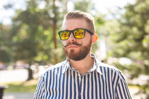 Sıcak güneşli bir yaz gününde parkta yürüyen olumlu neşeli bir genç adamın portresi. Çalışma sonrası dinlenme kavramı ve hafta sonları çalışma.