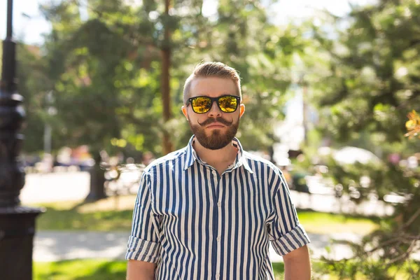 Retrato de un joven alegre y positivo caminando por el parque en un cálido día soleado de verano. El concepto de descanso después del estudio y el trabajo los fines de semana . — Foto de Stock