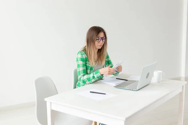 La jeune femme énervée considère le montant des dépenses pour les achats et le paiement des crédits en entrant des informations dans l'ordinateur portable pour la comptabilité de la tenue de livres à domicile. Concept d'économies et de déchets . — Photo