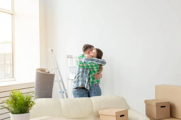 Молода пара обіймає і танцює у вітальні своєї нової квартири. Концепція доступної іпотеки та нового житла для молодої сім'ї . — стокове фото