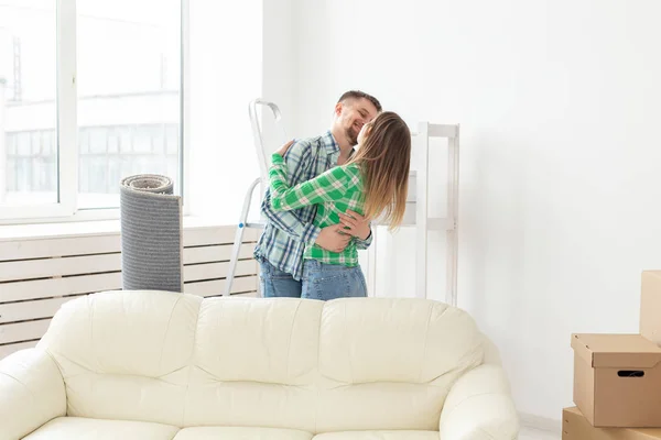 Niet geïdentificeerde jonge paar omarmt en danst in de woonkamer van hun nieuwe appartement. Het concept van betaalbare hypotheek en nieuwe huisvesting voor een jong gezin. — Stockfoto