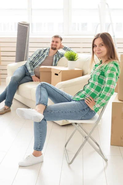 Jovem sorridente positiva sentada contra seu marido enevoado rindo em uma nova sala de estar enquanto se muda para uma nova casa. O conceito de alegria a partir da possibilidade de encontrar novas habitações . — Fotografia de Stock