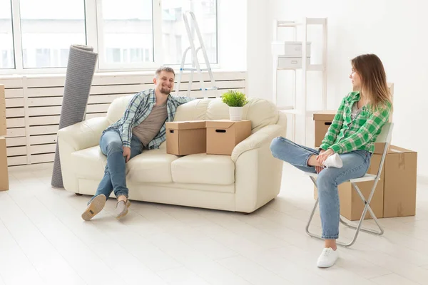 Casal alegre positivo se alegra em mover seu novo apartamento sentado na sala de estar com seus pertences. Conceito de aquecimento doméstico e hipotecas para uma família jovem . — Fotografia de Stock