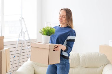 Büyüleyici genç bekar kadın onu gri lop kulaklı İskoç kedi yanında yeni bir dairede ayakta iken hareket ederken şeyler ile bir kutu tutar. Hareketli ve housewarming kavramı.