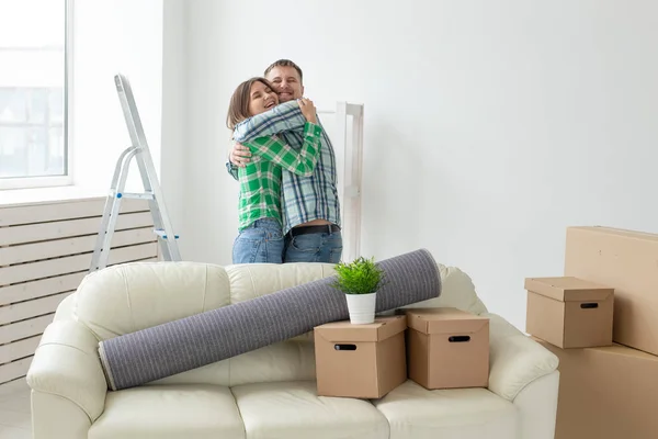 Jong paar in denim broek omarmen blijdschap in hun nieuwe appartement tijdens de verhuizing. Het concept van Housewarming en krediet voor nieuwe woningen. — Stockfoto