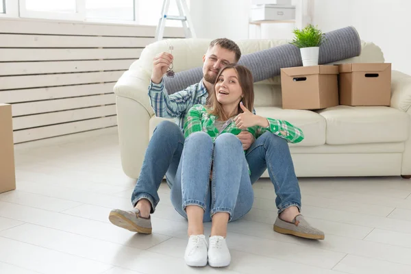 Молода позитивна пара тримає ключі від нової квартири, стоячи у своїй вітальні. Концепція побудови та іпотеки сім'ї . — стокове фото