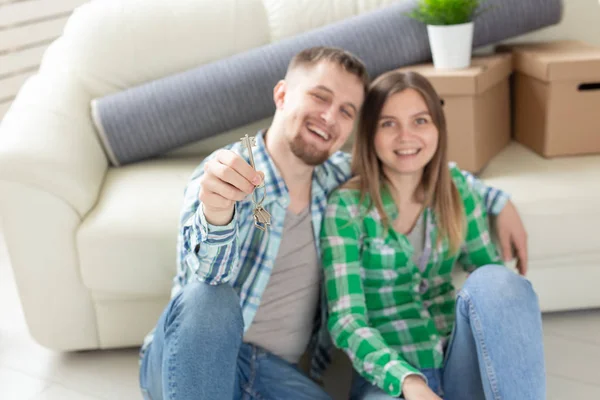 거실에 서있는 동안 새로운 아파트의 열쇠를 들고있는 젊은 긍정적 인 부부. 집안일 및 가족 모기지 개념. — 스톡 사진