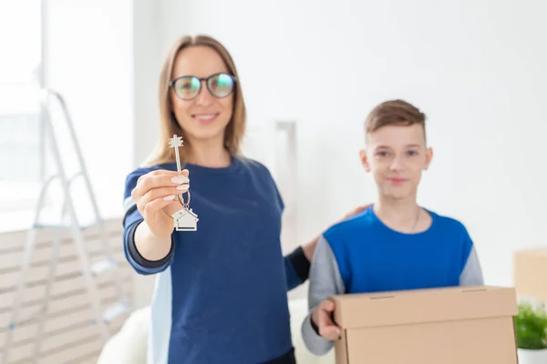 Blurry good looking mom and son are holding the keys to a new apartment after the housewarming. New concept and mortgage options for a young family. Single parent — Stock Photo, Image