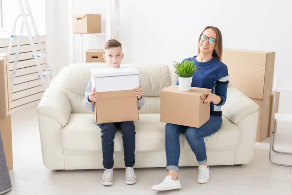 Bonito mãe solteira e pequeno filho classificar caixas com coisas após a mudança. O conceito de habitação hipotecária e a alegria de novas habitações . — Fotografia de Stock