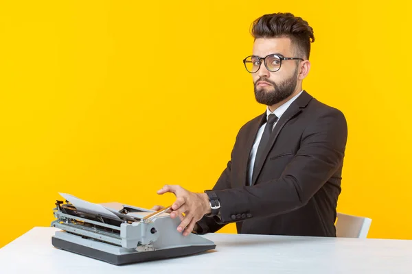 Vista lateral de un joven y encantador hombre de negocios con atuendo formal y gafas escribiendo en un texto de máquina de escribir. Concepto de negocios e ideas . — Foto de Stock