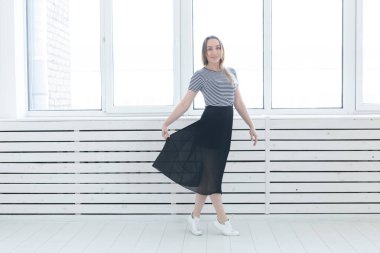 Gençlik, stil ve insan kavramı - siyah etek ve spor ayakkabı pencerenin yanında duran genç kadın