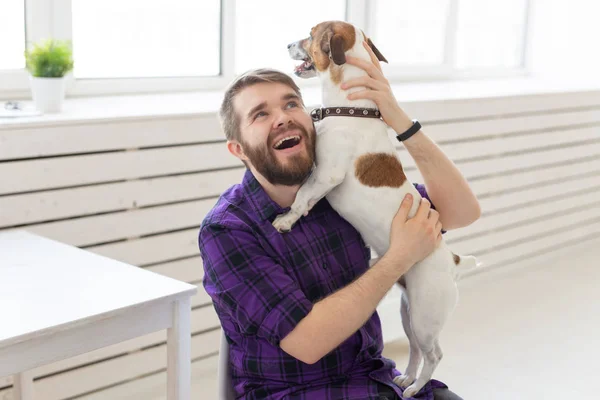 People, pets and home concept - young man playing with jack russell terrier puppy on white background — Stock Photo, Image