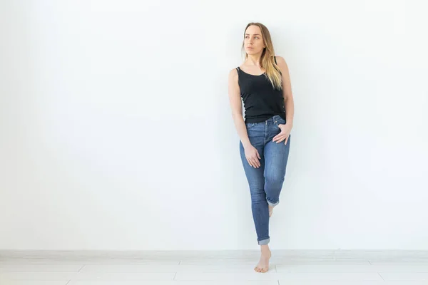 Стиль, концепция людей - молодая женщина в джинсах и черной рубашке, стоящая на белом фоне с пространством для копирования — стоковое фото