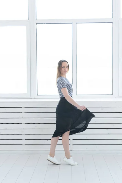 Juventude, estilo e conceito de pessoas - jovem mulher em saia preta e tênis de pé perto da janela — Fotografia de Stock