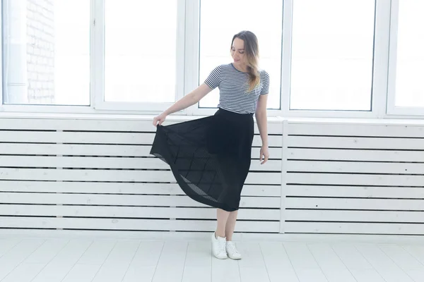 Ungdom, stil och människor Concept-ung kvinna på svart kjol och sneakers stående nära fönstret — Stockfoto