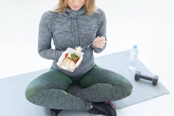 sport, healthy, people concept - Close-up of girl holding salad and dumbbell after fitness training