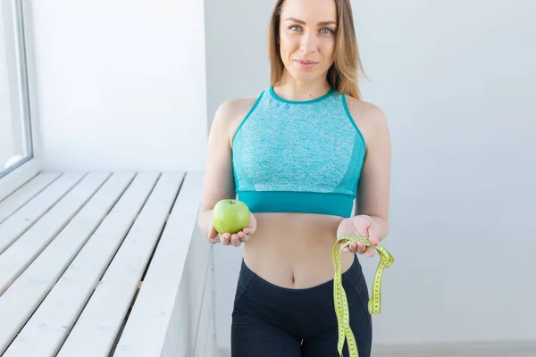 Stile di vita sano, dieta, perdita di peso e concetto di persone donna fitness con metro e mela sorridente felice guardando la fotocamera — Foto Stock
