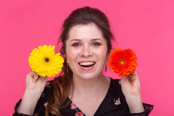 Summer, flowers and people concept - woman with gerberas over the pink background