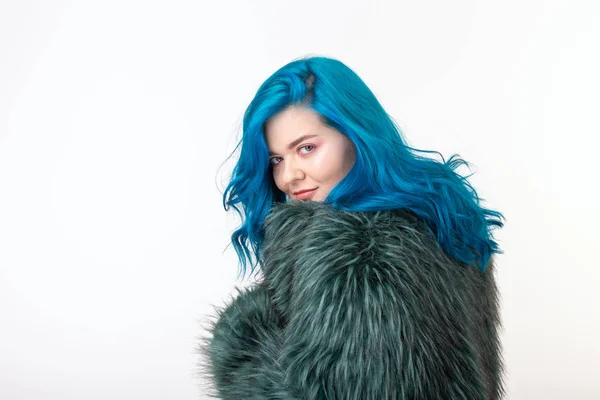 Proteção animal, moda e conceito de pessoas - menina bonita vestida com casaco de pele artificial com cabelo azul em pé sobre fundo branco — Fotografia de Stock