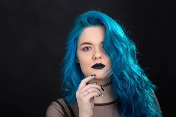 People and fashion concept - Young and attractive woman with black lipstick and blue hair posing over black background — Stock Photo, Image