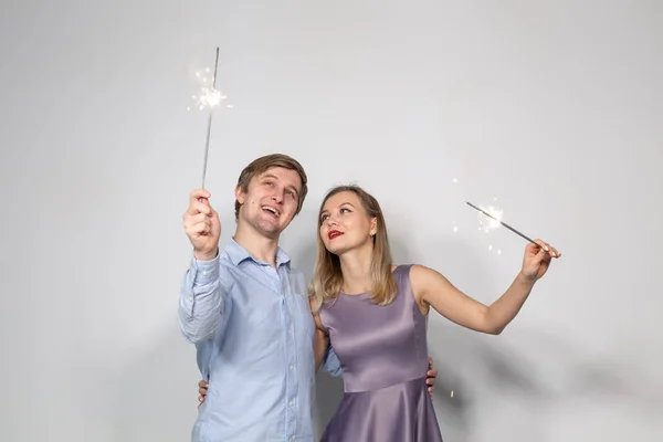 Conceito de festa, família e feriados - jovem casal celebrando seu aniversário com faíscas no fundo branco — Fotografia de Stock