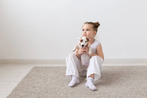 Mascotas, concepto de la infancia y los animales - Niña jugando en el suelo con el cachorro Jack Russell Terrier — Foto de Stock