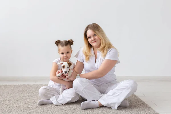 Concept de personnes, de famille et d'animaux de compagnie - mère et fille assises par terre avec le chiot Jack Russell Terrier — Photo
