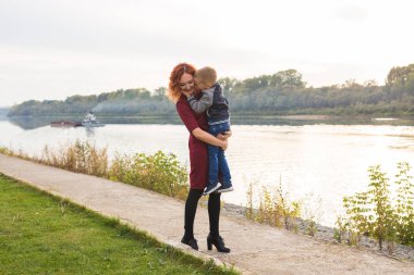 Aile ve çocuk kavramı - oğlu su arka plan üzerinde tutan Kızıl saçlı kadın