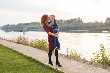 Annelik ve çocuk kavramı - genç anne ile oğlu Nehri yakınında kollarında