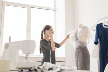 Terzi, terzi, moda ve showroom konsept - güzel genç tasarımcı cep telefonda konuşurken ve terzilik stüdyo işinde incelenirken gülümseyen