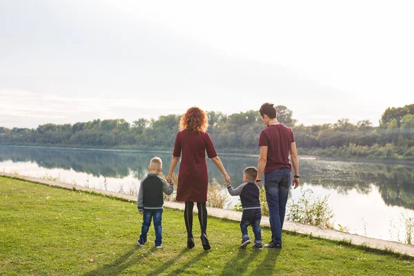 Parenthood and nature concept -Family of mother and father with two boys twins kids in a park at summer by a river at sunny day — Stock Photo, Image