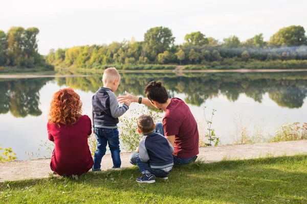 Barn, föräldraskap och naturen koncept - stor familj sitter på gräset — Stockfoto