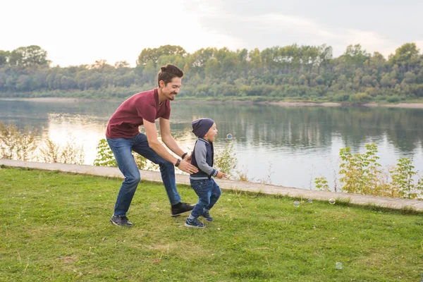 Concept de parentalité et d'enfants - Père jouant avec un petit fils, essayant de l'attraper — Photo