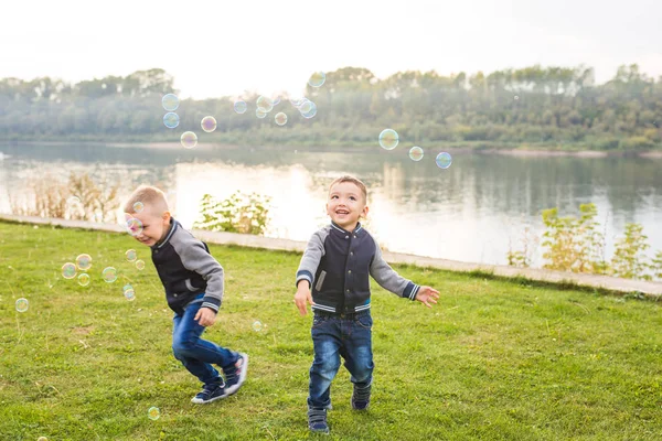 Crianças e conceito de infância - Dois irmãos meninos brincando com bolhas de sabão coloridas — Fotografia de Stock