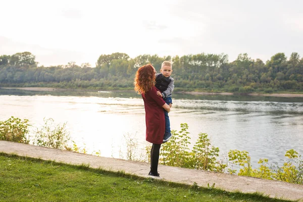 Mutterschafts- und Kinderkonzept - junge Mutter mit Sohn im Arm in der Nähe des Flusses — Stockfoto