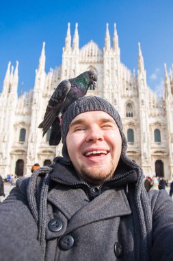 Kış seyahat, tatil ve kuşlar kavramı - selfie güvercinler yakınındaki Milan Katedrali Duomo di Milano, İtalya ile alarak genç komik adam.