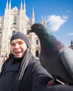 Kış seyahat, tatil ve kuşlar kavramı - yakışıklı erkek turist Milano'da ünlü Duomo Katedrali önünde selfie fotoğraf yapma komik güvercinler ile.