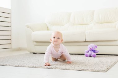 Yerde evde gülümseyen sürünen bebek kız